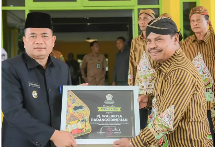 Ketua DPD Pujakesuma Kota Padangsidimpuan, Purnadi, menyerahkan cinderamata kepada Pj Wali Kota Padangsidimpuan Timur Tumanggor, usai beraudensi, di aula Sekretariat Korps Pegawai Republik Indonesia (KORPRI) di Kantor Wali Kota Padangsidimpuan, Senin (29/7/2024).(Realitasonline.id/ RI)