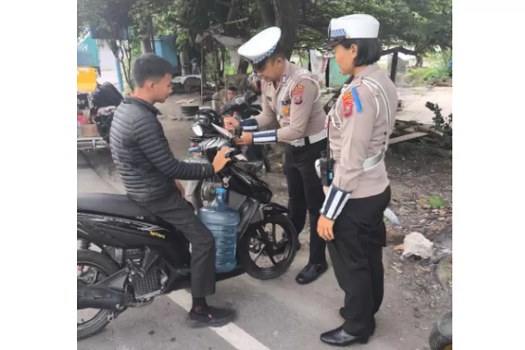 Personel Polisi menilang pengendara yang tidak memakai helm pada Operasi Zebra Toba 2024.