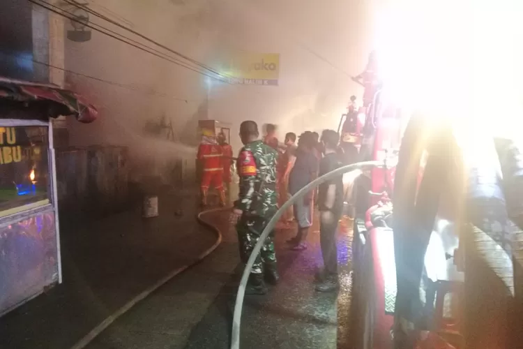 Petugas damkar berusaha memadamkan kobaran api yang menghanguskan toko menjual bahan makan dan jajanan di Pancu (Realitasonline.id/zul)
