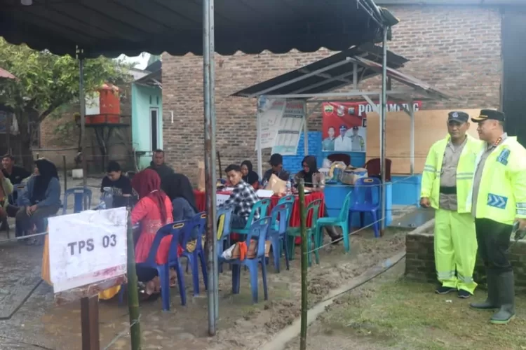 Kapolresta Deli Serdang Kombes Pol  Raphael Sandhy Cahya Priambodo SIK didampingi seorang personilnya meninjau langsung ke TPS (pakai mantel hujan warna hijau) (Realitasonline.,id/zul)