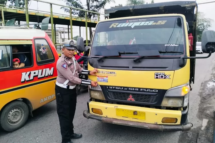 Personil Sat Lantas Polresta Deli Serdang menempelkan stiker himbauan kepada angkutan truk di jalinsum Simpang Tanjung Garbus Lubuk Pakam