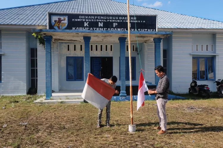 Hoirul Umam saat melakukan penggantian bendera merah putih yang rusak dan robek dikantor DPD KNPI Paluta, Rabu (7/5/2025).