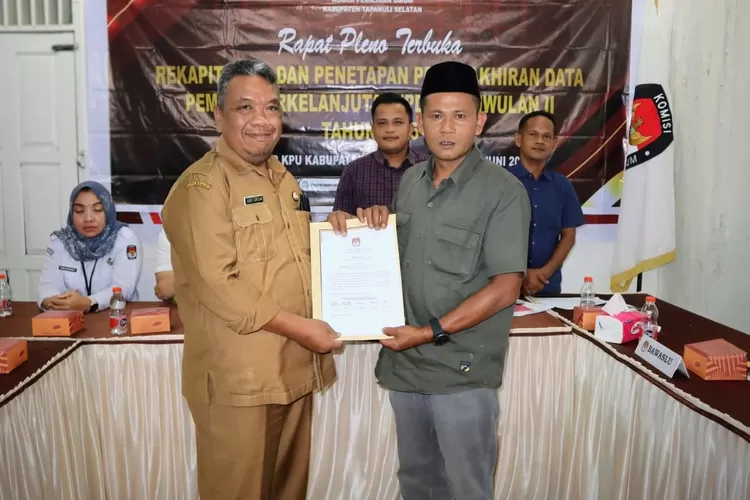 Ketua KPU Kabupaten Tapsel Zulhajji Siregar serahkan dokumen DPB Triwulan II 2025 kepada Pemkab Tapsel diterima Kadis Kependudukan dan Pencatatan Sipil Tapsel Abadi Siregar, usai Rapat Pleno Terbuka di Aula Kantor KPU Kabupaten Tapsel, Desa Situmba, Sipirok, Senin (30/6/2025).(Realitasonline.id - RI