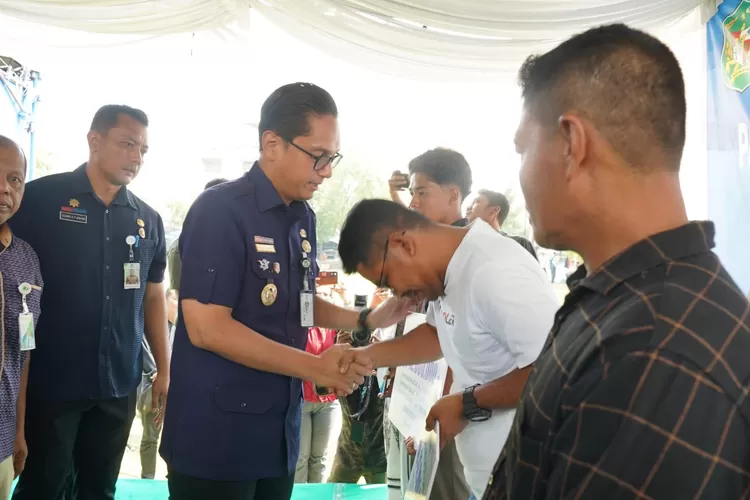 Walikota Rico Waas menyerahkan klaim asuransi kematian dari BPJS  Ketenagakerjaan dan bantuan sosial lainnya, di lapangan bola Medan Marelan, Selasa (29/7/2025).