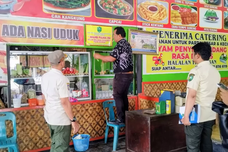 Personil gabungan dari Satpol PP dan Bakeuda Padangsidimpuan tempelkan stiker penunggak pajak, dalam satu operasi di Kota Padangsidimpuan, Jumat (19/9/2025).(Foto : Realitasonline / Riswandy)