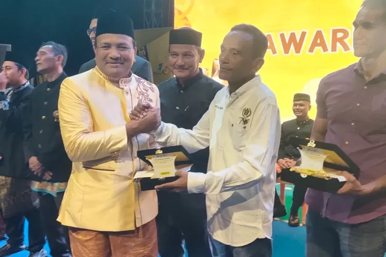 Ketua PWI Bireuen, Ariadi B  Jangka menerima plakat penghargaan dari Pemkab Bireuen yang diserahkan Bupati Bireuen, H Mukhlis. Foto; RZ