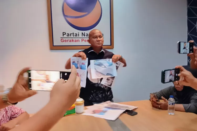 Ketua Fraksi NasDem DPRD Sumut yang juga Ketua DPD Partai NasDem Tapteng Rahnabsyah Sibarani SH MH saat memperlihatkan foto kendaraan keluarganya rusak dan  foto beberapa korban luka-luka (Realitasonline.id/Dok)
