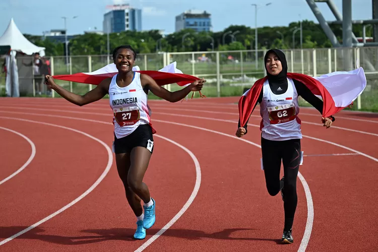 Pelari puteri Indonesia Shava S Warangga (kanan) bersama Danselina Tauruy (kiri) selebrasi berlari dengan bendera merah putih usai pada final sprint 100 meter U-18 puteri event kejuaraan Atletik Asia Tenggara U-18 &amp; U-20 di Stadion Madya Atletik Kawasan Sport Centre Sumut, Kabupaten Deliserdang, 