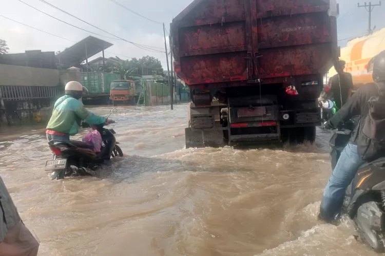 Kondisi banjir di ruas jalan provinsi Kl Yos Sudarso Simpang Titipapan dan Simpang Dobi terendam air setinggi betis hingga paha orang dewasa, Rabu (3/12/2025) pagi. Hingga kini air belum tampak surut. (Realitasonline.id/ AH)