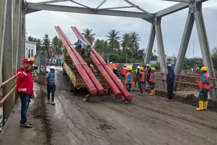 Truk pengangkut tiang listrik sempat tersangkut pada tanjakan jembatan Bailey di Teupin Mane Kecamatan Juli. Tetapi setelah dibantu Operator Kran akhir bisa melewati jembatan tersebut. Foto; AJ