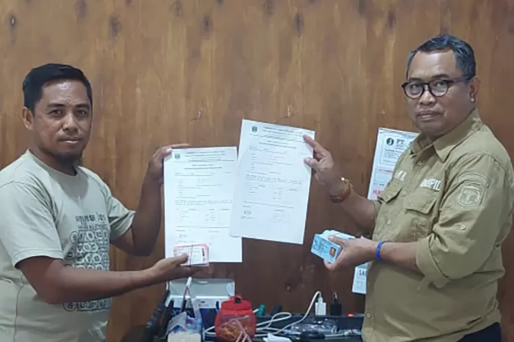 Kadisdukcapil, Kasrum, saat menyerahkan dokumen kependudukan kepada Kades Muktijaya (Istimewa)