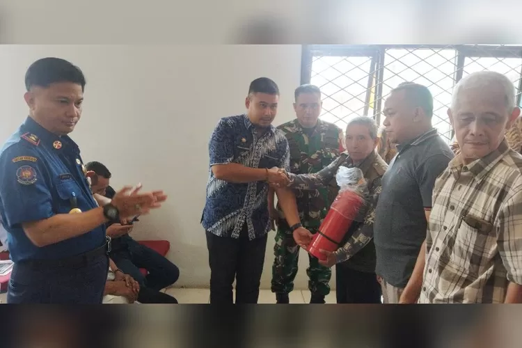Lurah Kebalen, Firman Arief Sembada disaksikan Kepala Dinas Damkar Kabuapaten Bekasi H Adeng Hudaya secara simbolis menyerahkan APAR kepada Ketua RW 