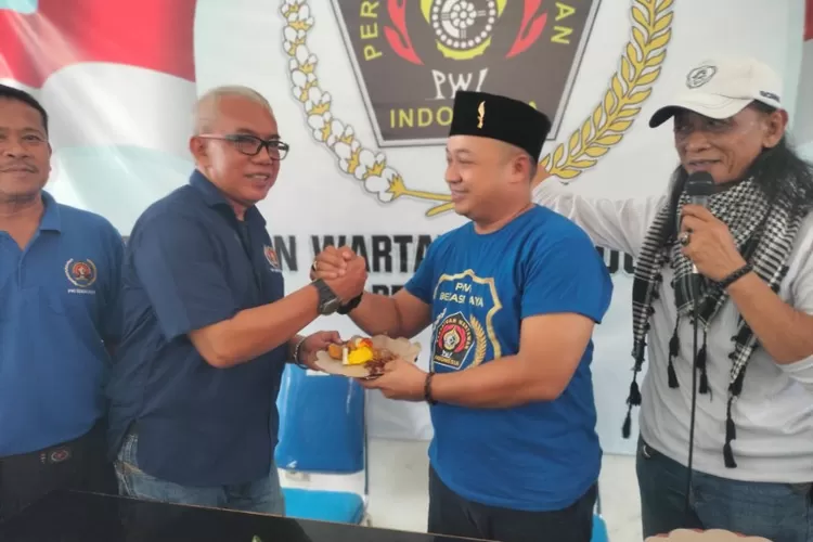 Ketua PWI Bekasi Raya Ade Muksin memberikan potongan nasi tumpeng kepada L Budiarto (Budhie Uband), Wakil Ketua III PWI Bekasi Raya
