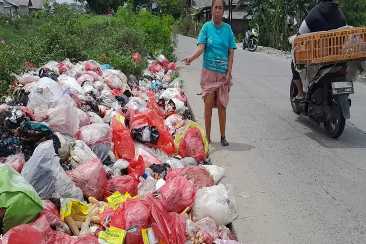Karwati warga Desa Kedung Jaya, Kecamatan Babelan sedang menunjukan tumpukan sampah yang berada di pinggir Jalan Pertamina,  Wates Kecamatan Babelan, Rabu (5/11/25). (Karta Sasmita/satuarah.co)