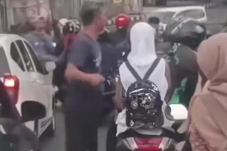 Tangkapan layar video viral di Cibinong memperlihatkan seorang pengemudi mobil memukul driver ojol di jalan raya. Polisi kini melakukan penelusuran terkait insiden tersebut. (Foto/Instagram - Bangsaonline)