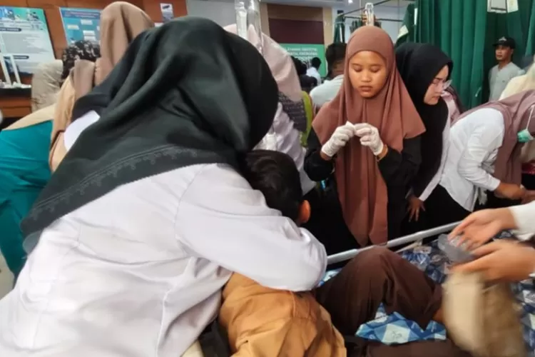 Petugas kesehatan memeriksa siswa sekolah dasar yang diduga keracunan setelah mengonsumsi makanan dari program makan bergizi gratis (MBG). Foto: Antara.