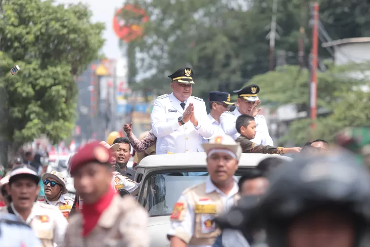 Bupati dan Wakil Bupati Bogor Rudy Susmanto - Ade Ruhandi menyapa warga yang menyambutnya di sepanjang jalan saat menuju Gedung Tegar Beriman, Cibinong, Kamis, 20 Februari 2025. (Diskominfo)
