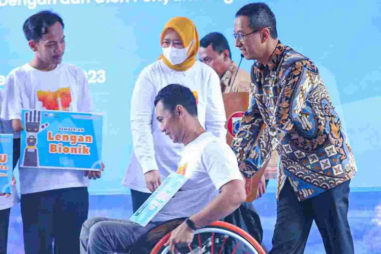 Pj Gubernur DKI Jakarta Heru Budi Hartono mendorong kursi roda salah seorang penyandang disabilitas dalam kegiatan di Balai Kota DKI, Kamis ( 7/12/2023).