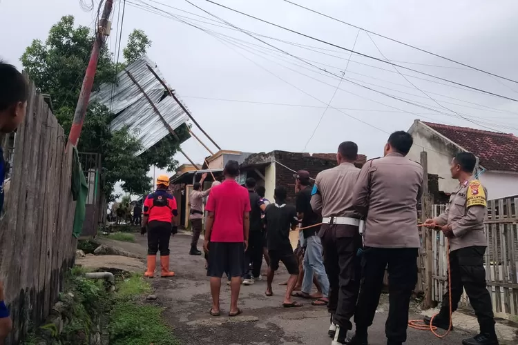 Warga fibac uf polisi di Sumbawa menurunkan atap rumah terbang nyangkut di pohon akibat terjangan angin kencang disertai hujan. (Suara Karya/Ist)