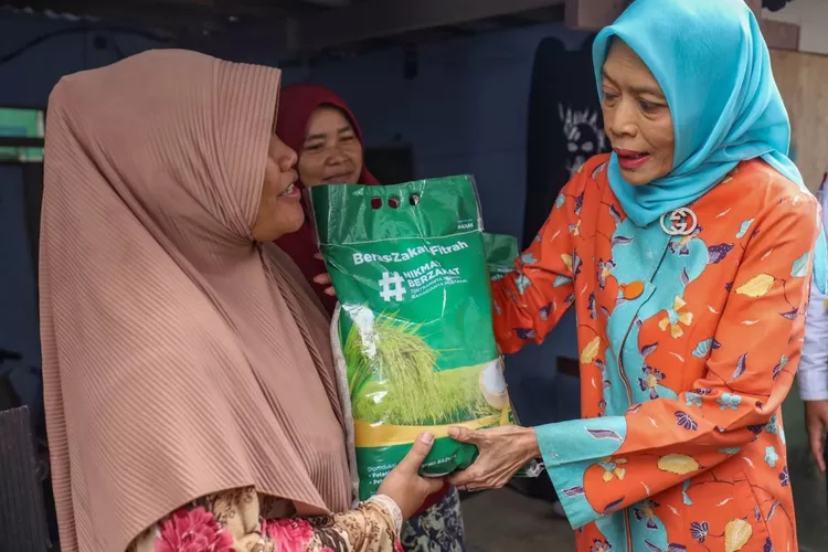 Pimpinan Baznas Bidang Pendistribusian dan Pendayagunaan Saidah Sakwan menyerahkan  satu kantong plastik beras premium kepada salah seorang warga Lampung Mongol, Kelurahan Tegalluga, Bogor, Senin ( 1/4/2024).