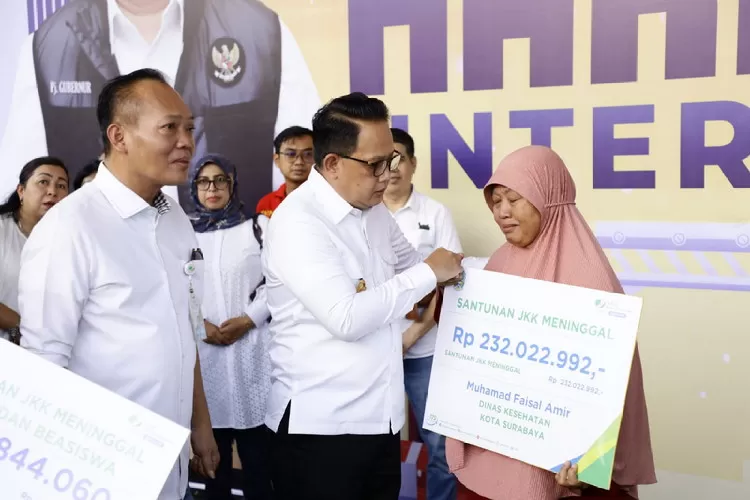 Pj Gubernur Jatim, Adhy Karyono didampingi Kepala Kantor Wilayah BPJS Ketenagakerjaan Jawa Timur, Hadi Purnomo saat menyerahkan manfaat program di Hari Buruh Internasional