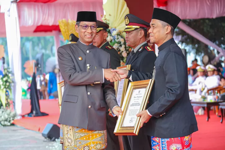 PJ Gubernur DKI Jakarta Heru Budi Hartono ( kiri) menyerahkan penghargaan kepada Kejati DKI Jakarta atas sinerginya pada HUT ke 497 Kota Jakarta,di Monas, Jakarta Pusat, Sabtu (22/6/2024).