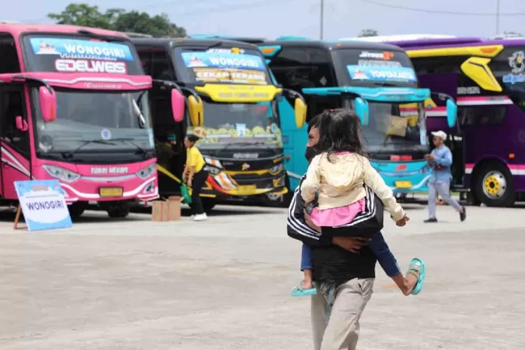 Warga menggendong anak kecil melintas di depan sejumlah bus.  (ANTARA/HO-Humas Kemenhub )