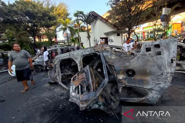 Sejumlah warga melihat kondisi bangkai mobil terbalik usai pembakaran Kantor DPRD Kota Makassar oleh massa di Jalan Andi Pangeran Pettarani Makassar, Sulawesi Selatan.  (ANTARA/Darwin Fatir)