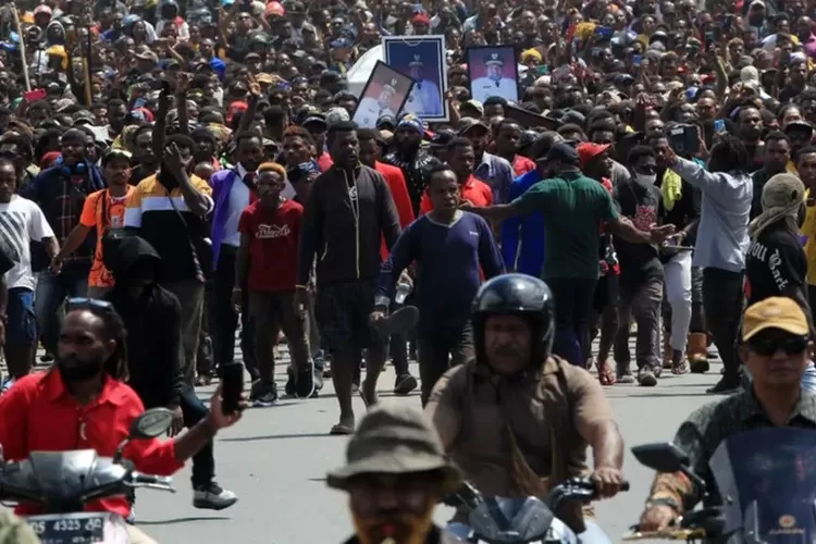 Arak-arakan massa saat mengantar jenazah Mantan Gubernur Papua Lukas Enembe ke ke persemayaman di Sekolah Tinggi Agama Kristen Protestan Negeri (STAKIN), Sentani, Papua, yang berjarak sekitar tiga kilometer dari Bandara Sentani.