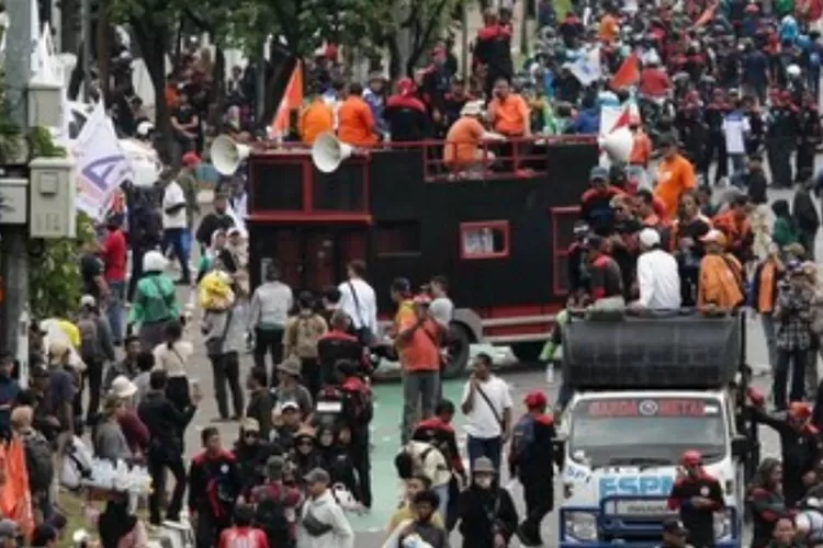 Ribuan buruh berunjuk rasa di depan DPR membawa spanduk tuntutan. (HukamaNews.com / Tangkapan layar)