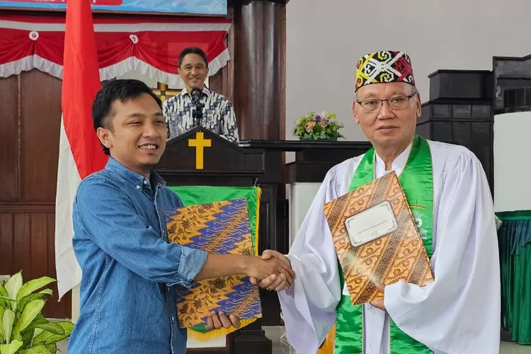 Community Officer GreenFaith Indonesia Syahrul Ramadhan berjabat tangan dengan Pdt. Manuel E. Raintung, Ketua II Majelis Sinode GPIB Bidang Gereja, Masyarakat, Agama-Agama, dan Lingkungan Hidup (GERMASA-LH) pasca menandatangan MOU tentang program kerja sama di bidang lingkungan hidup.