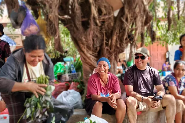 Adrianus Garu (baju kaus hitam) berbincang dengan pedagang pasar sambil menunggu sayur yang dibelinya.