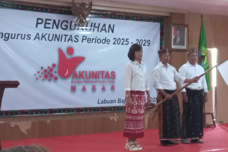 Ketua Akunitas Mabar yang baru periode 2025-2029 Adrianus, tengah (pegang bendera) didampingi wakil ketua (kanan) dan mantan ketua periode sebelumnya, Candi (kiri). (Foto: KLIKLABUANBAJO.ID)