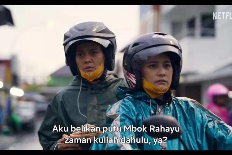 Gambar ini menampilkan dua tokoh dalam film Budi Pekerti yang sedang mengenakan jas hujan dan helm, kemungkinan di tengah perjalanan saat hujan. Ekspresi mereka terlihat serius dan fokus, seolah berada di momen penting yang memicu jalannya cerita. (Foto/YouTube - @NetflixIndonesia.)