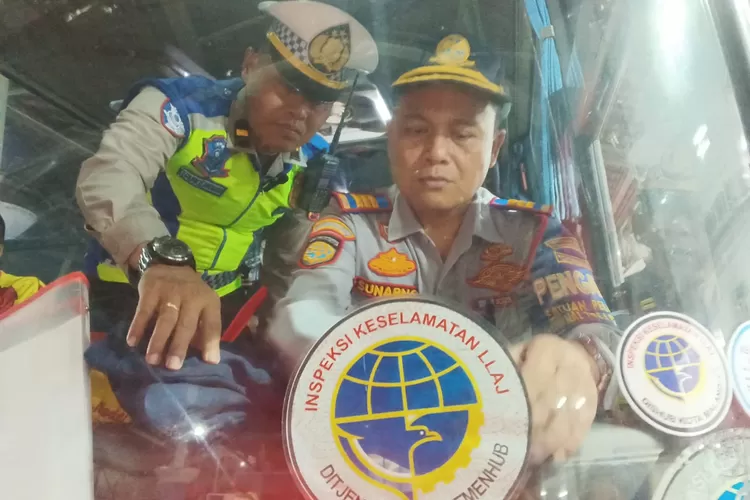 PASANG STIKER : Kepala Terminal Kota Pekalongan Sunarno, didampingi petugas Lantas Polres Pekalongan Kota saat memasang stiker Inspeksi Keselamatan Lalu Lintas Angkutan Jalan (LLAJ) di depan kaca bus. (KONTENJATENG.COM/Arif Prayoga)