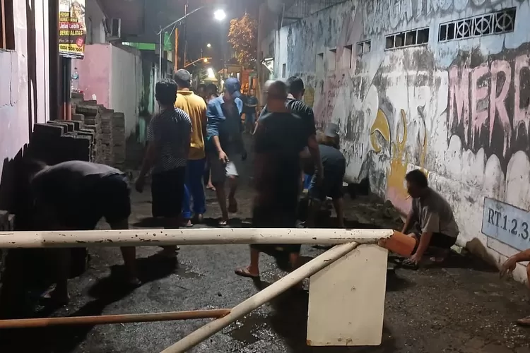 Masyarakat RW 04 Desa Trosobo Kecamatan Taman melakukan kerja bakti meninggikan dan mengganti paving yang rusak, Sabtu 10 Mei 2025. 