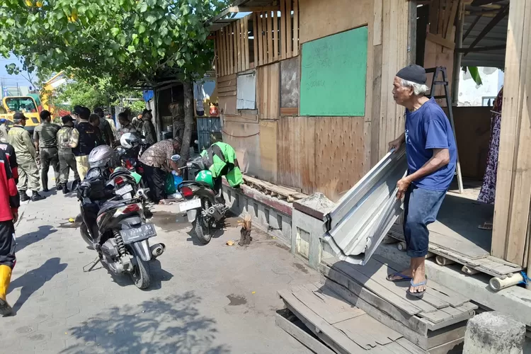 Seorang warga memunguti sisa-sisa barang di lapaknya yang berlokasi di Kaligawe Semarang. Lapak tersebut dirobohkan karena dinilai jadi penyebab banjir. (Ayosemarang.com/ Audrian Firhannusa)