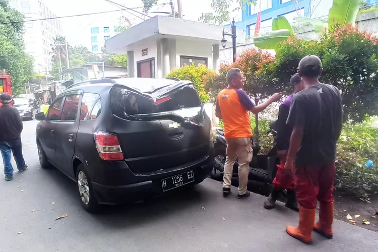 Mobil milik Kepala Sekolah SMK Bhakti Nusantara yang tertimpa pohon tua. (Istimewa)