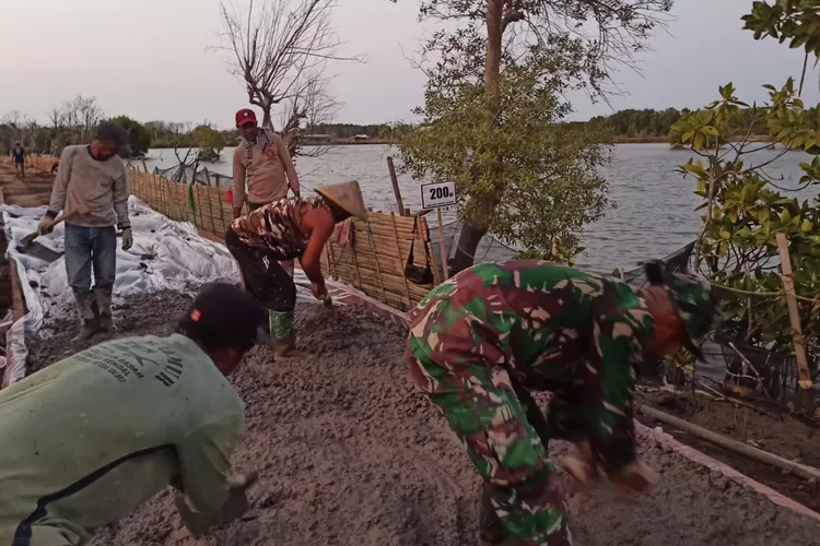 Masyarakat bersama TNI bergotong royong membuat jalan beton di Desa Kartika Jaya Patebon dalam program TMMD.  (Dokumen Diskominfo)