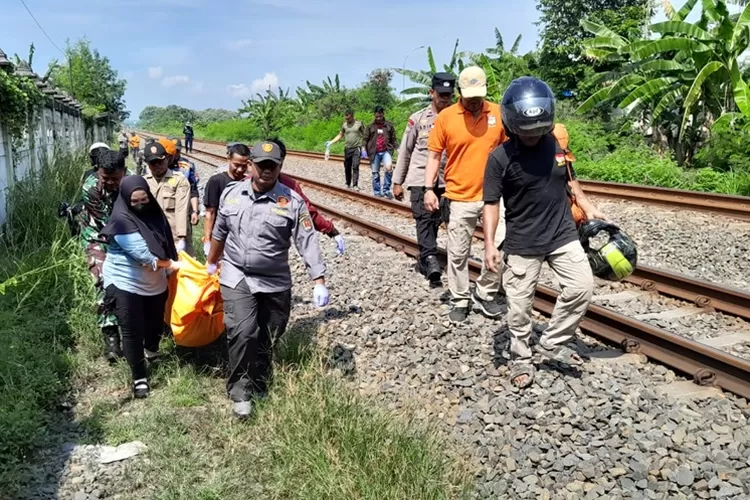 Petugas mengevakuasi mayat lelaki paruh baya yang tewas tertemper kereta. Korban tubuhnya hancur.  (Ayosemarang.com/ Audrian Firhannusa)