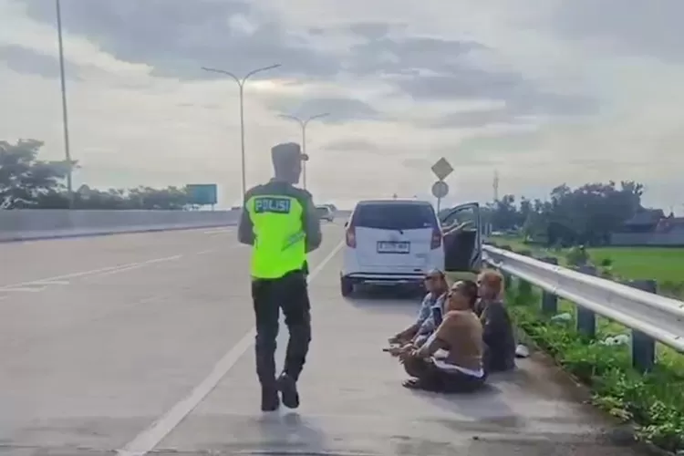 Petugas kepolisian saat menegur pemudik yang istirahat di bahu jalan Tol. Polda Jateng meminta pemudik tidak melakukan ini karena membahayakan.  (Polda)