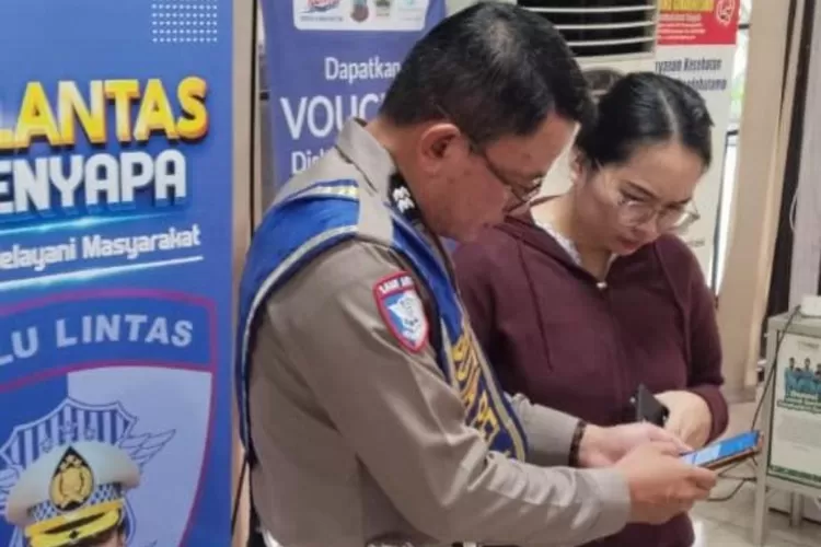 Petugas Samsat menyampaikan cara penggunaan aplikasi SIGNAL kepada salah satu warga. (dok.)