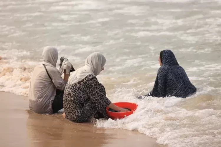 Perempuan di Gaza mencuci pakaian dengan air laut karena minimnya air bersih.  (Sumber: Mahmud Hams via AlJazeera)