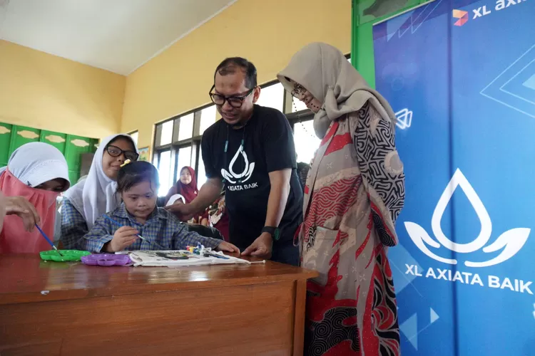 Head Facility Planning &amp; Development XL Axiata, Eka Madiyanto (kedua dari kanan), bersama Kepala Sekolah SLB C Nusantara Kita Garut, Jawa Barat, Euis Sugihartati (kanan) mendampingi salah seorang pelajar di Sekolah Luar Biasa C Nusantara Garut, Jawa Barat, Sabtu (2/12). (XL AXIATA)