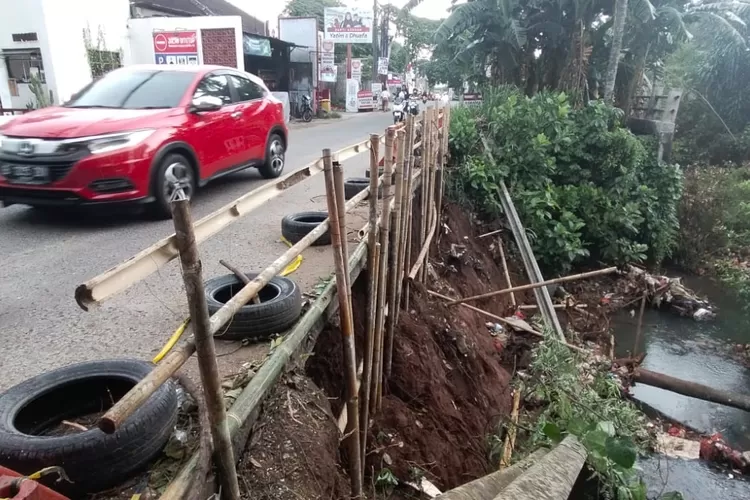 Jalan Raya Krukut, Kelurahan Krukut, Limo, Kota Depok, yang menghubungkan Kelurahan Grogol longsor hingga tanah di bawah jalan tergerus.  (FAHMI/RADAR DEPOK)