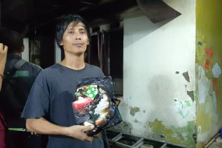 Sandi Kurniawan (40) penghuni rumah yang terbakar di Gang Langgar, Kelurahan Pondok Cina, Kecamatan Beji saat menunjukan Alquran yang selamat, Kamis (25/1). (GERARD SOEHARLY/RADAR DEPOK)