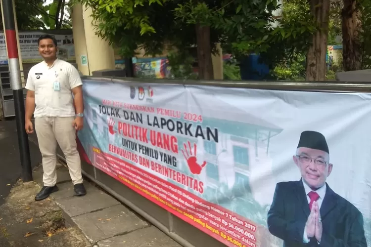 Lurah Tugu, Tri Sakti Anggoro, usai memasang spanduk ajakan untuk menolak politik uang di depan gedung kelurahan. (ANDIKA EKA/RADAR DEPOK)