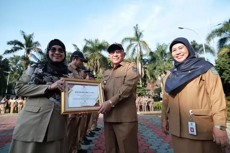 Walikota Depok, Mohammad Idris didampingi Plh Sekda Kota Depok, Nina Suzana menyerahkan Piagam Penghargaan pada Apel Pagi di Halaman Balai Kota Depok. (Pemkot Depok)