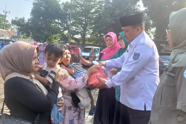 SIMBOLIS : Sekretaris Kecamatan Bojongsari, Suhendar saat memberikan paket pemberian makanan tambahan (PMT) lokal, berlangsung di pelataran kantor kecamatan, Rabu (10/7). (ALDY RAMA/RADAR DEPOK)