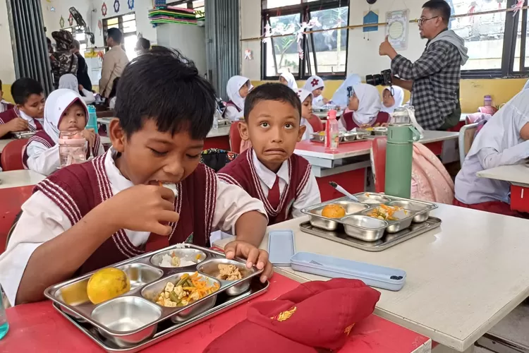 Pelaksanaan perdana program Makan Bergizi Gratis (MBG) di Kota Depok disambut bahagia ribuan anak SD di Kecamatan Tapos, Kota Depok, pada Senin (6/1). (ANDIKA EKA/RADAR DEPOK)